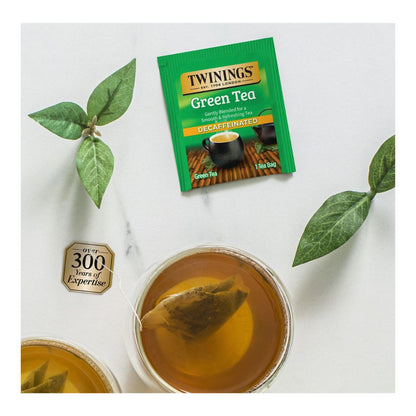 Twinings green tea package with a cup of tea and tea leaves on a white background