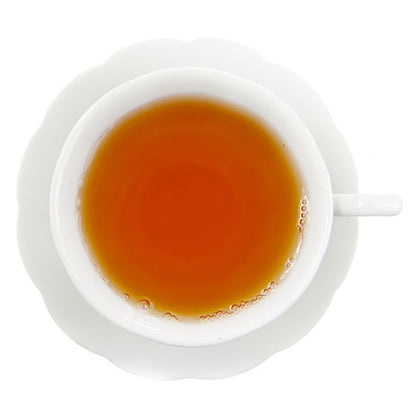 White cup and saucer with amber colored rooibos tea all on a white background