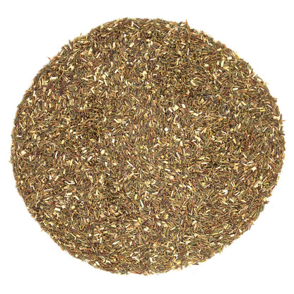 Round sample of dried beige and light brown tea leaves on a white background