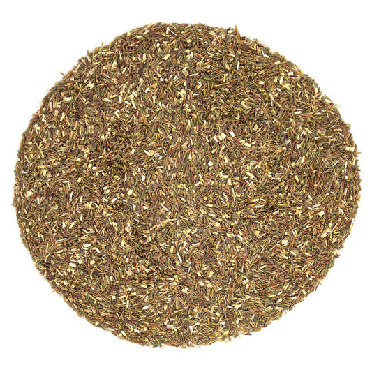 Round sample of dried beige and light brown tea leaves on a white background