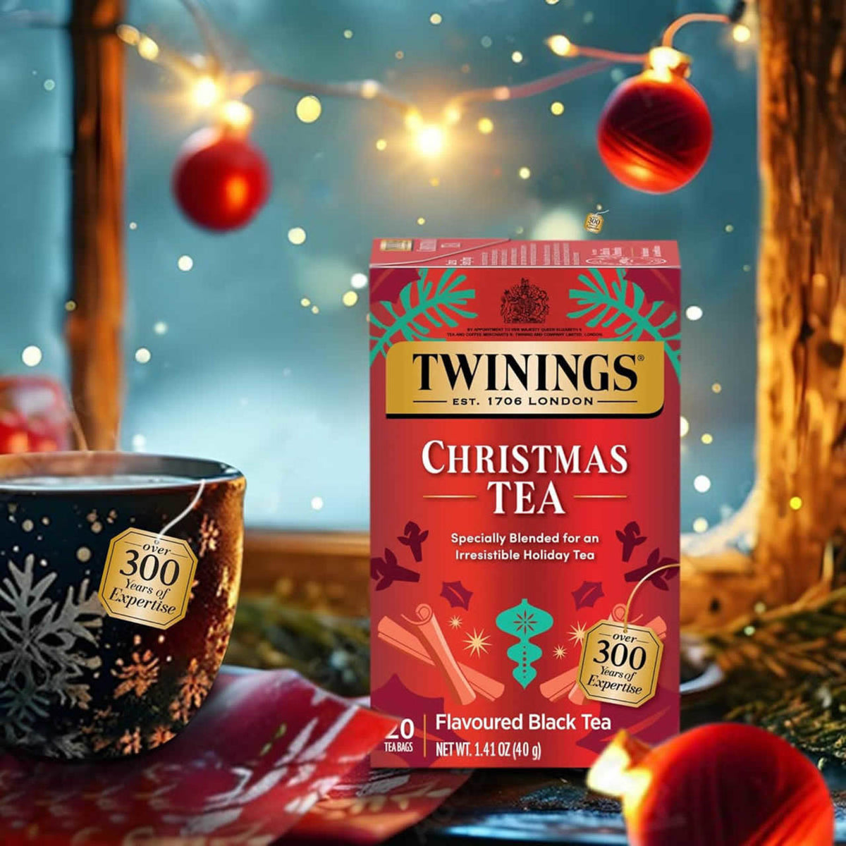 Twinings Christmas tea box with a festive background featuring lights and decorations.