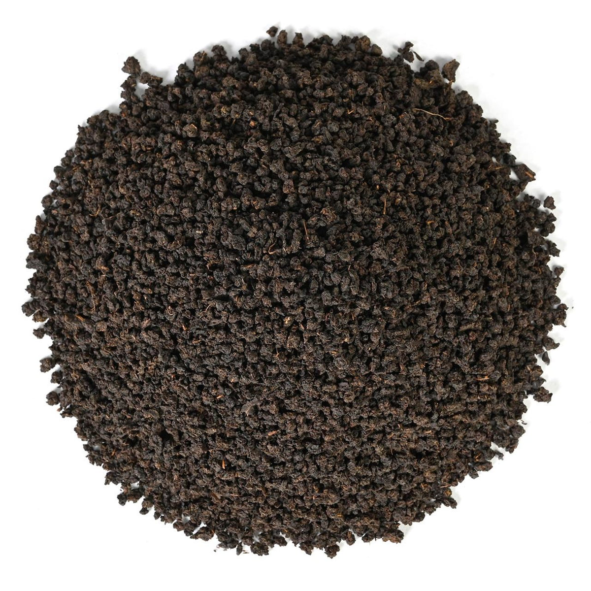 Round pile Irish Breakfast dry black tea leaves on a white background.