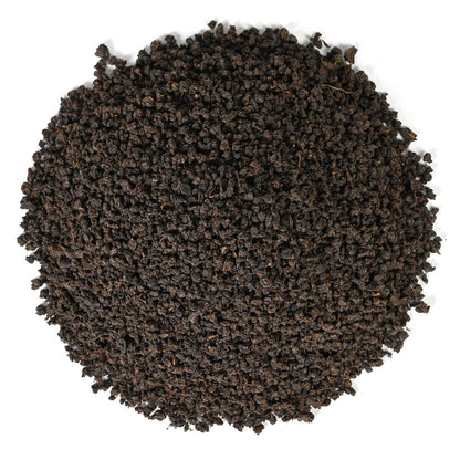 Round pile Irish Breakfast dry black tea leaves on a white background.