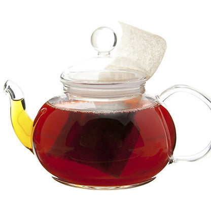Clear glass teapot with red colored hot tea and a tea bag on a white background