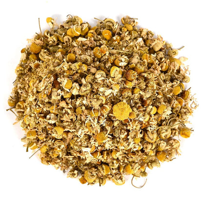 Pile of dried chamomile flowers and tea leaves on a white background