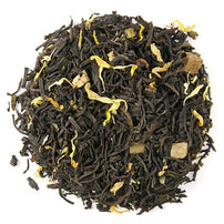 A close-up of loose leaf black tea with pieces of dried mango and lime leaves visible.