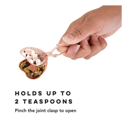 Rose gold heart-shaped tea infuser held by a hand with text on a white background