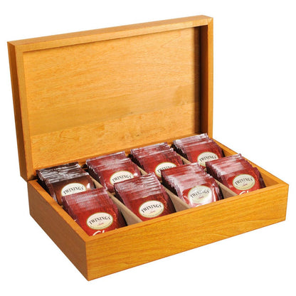 A wooden tea chest with multiple compartments, each filled with red Twinings Chai tea bags.
