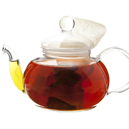 Clear glass teapot with a lid filled with amber colored tea on a white background