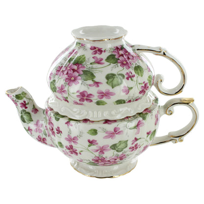 Porcelain floral-patterned teapot and matching cup on a white background
