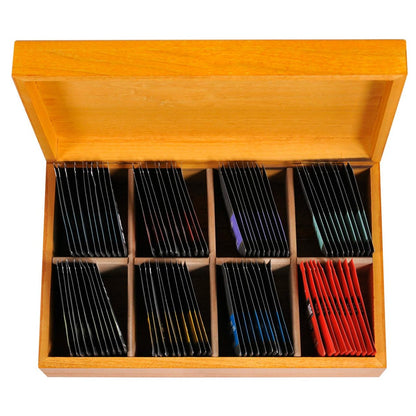 Light wooden tea box on a white background opened to show colorful individually wrapped teabags inside