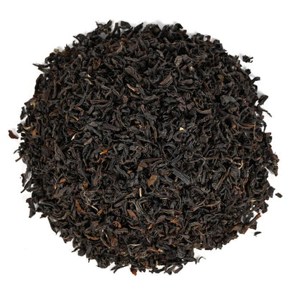 Round pile of loose-leaf black tea leaves on a white background.