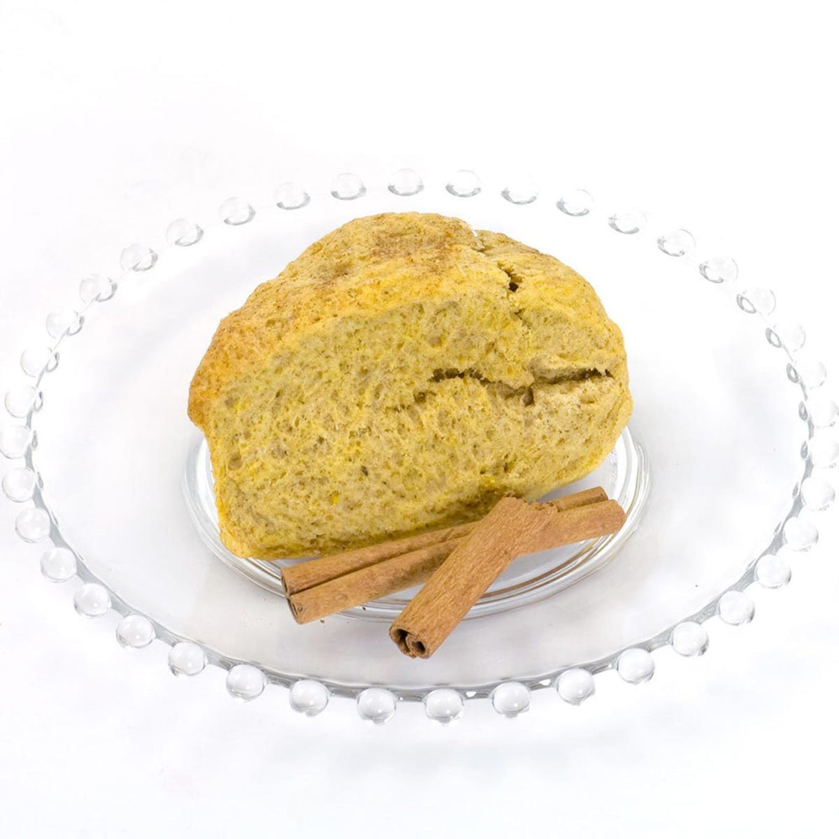 Pumpkin Spice Scone with two sticks of cinnamon on a glass plate on a white background