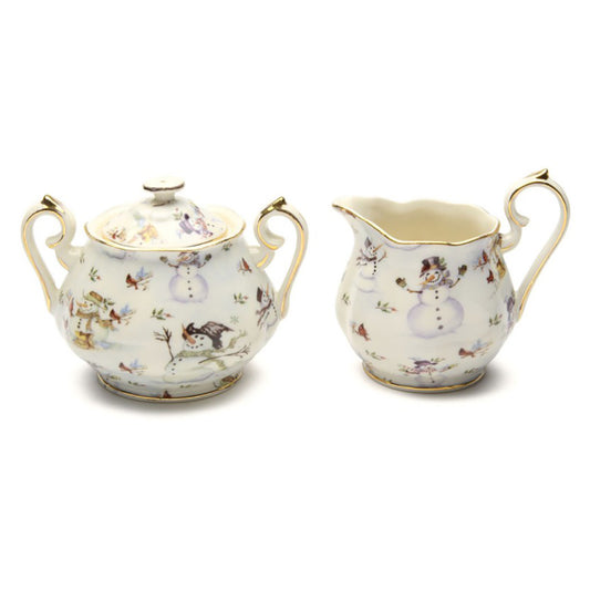 Decorative ceramic sugar bowl and creamer set with snowman design on a white background