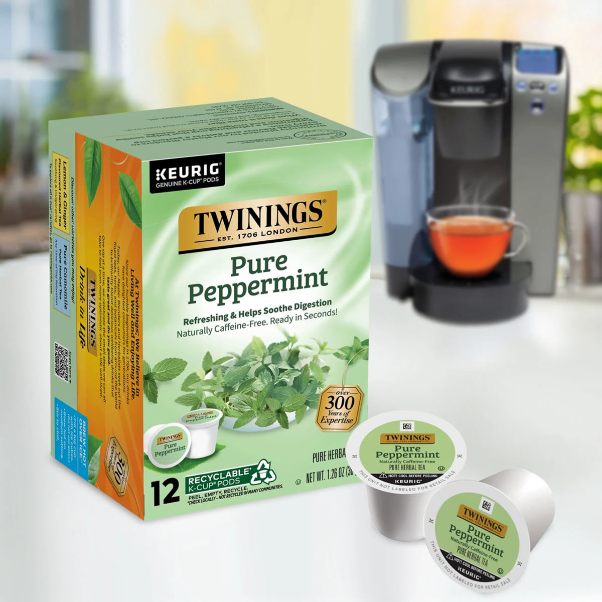 Box of Twinings Pure Peppermint Keurig tea pods with a coffee maker and cup in the background.