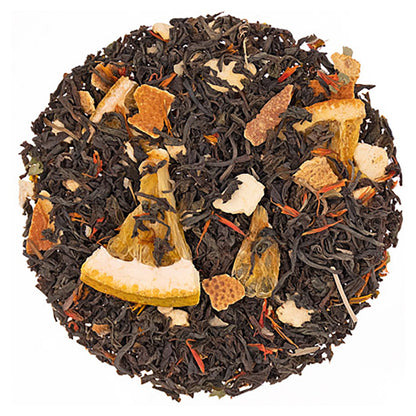 Tea ball with black tea leaves and various herbs on a white background