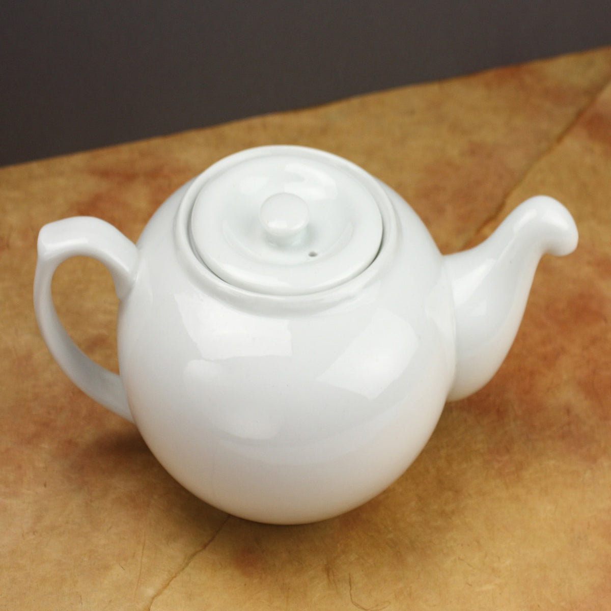 White ceramic teapot on a brown surface