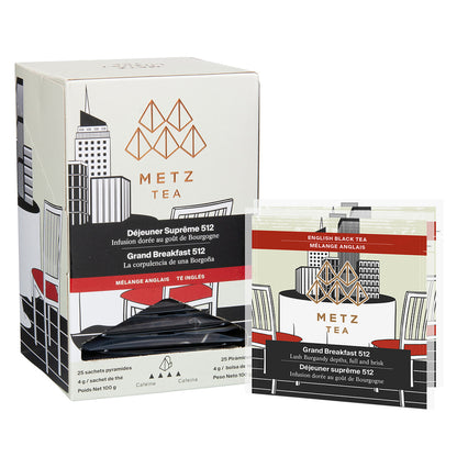 A box of Metz Grand Breakfast tea with illustrations of a city skyline and a chair with black and white color scheme and red accents.  Next to the box are a couple of individually wrapped teabags. 