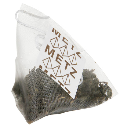 Pyramid style teabag with dry green tea leaves and a Metz label
