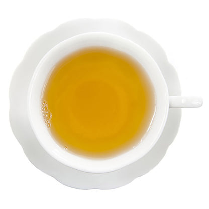 Top-down view of a white teacup on a white saucer on a white background filled with yellow colored hot tea