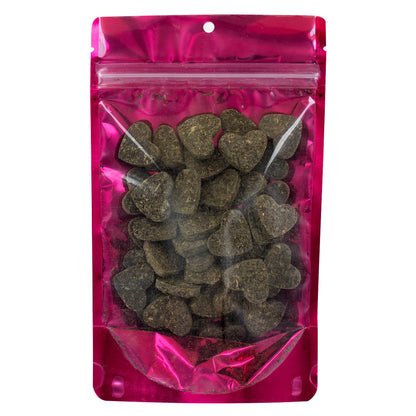 Pink transparent bag with heart-shaped dark green tea leaves pressed into hearts with the package on a white background