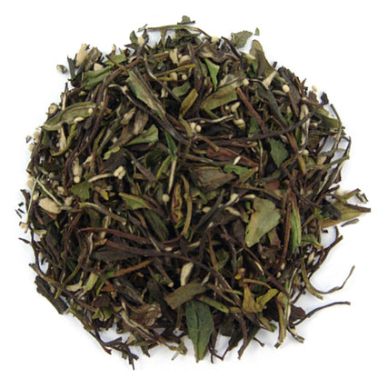 A pile of dry loose leaf tea with visible pieces of green tea leaves and small white tea buds.