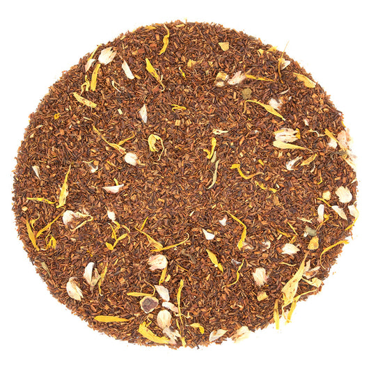 Round pattern of dry amber colored tea leaves on a white background