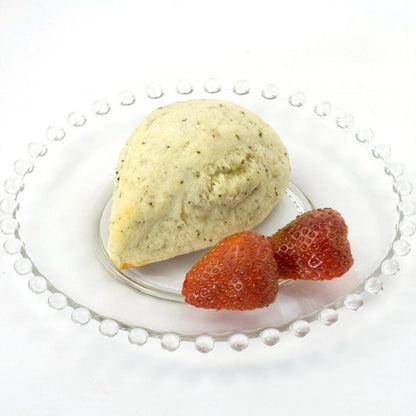 Indian Chai scone with two strawberries on a white plate with a pearl rim.