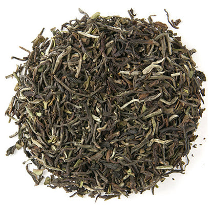 Top down view of dry green tea leaves in a circle pattern on a white background