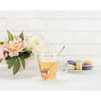 Tea cup with a floral arrangement and macarons on a white surface