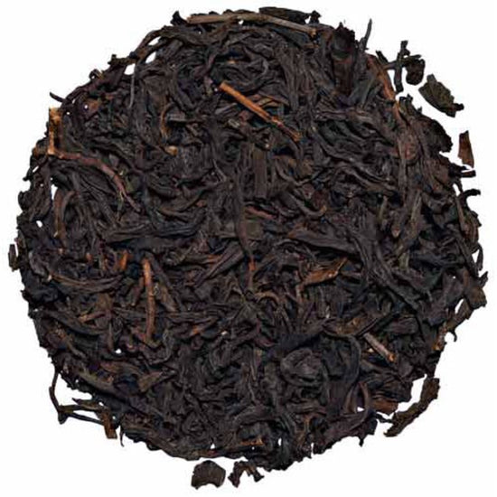 Close-up of dark brown tea leaves on a white background