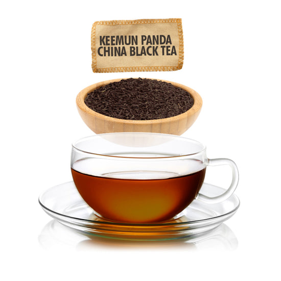 Clear glass teacup with black tea and a wooden bowl of loose tea leaves, with 'Keemun Panda China Black Tea' packaging above.