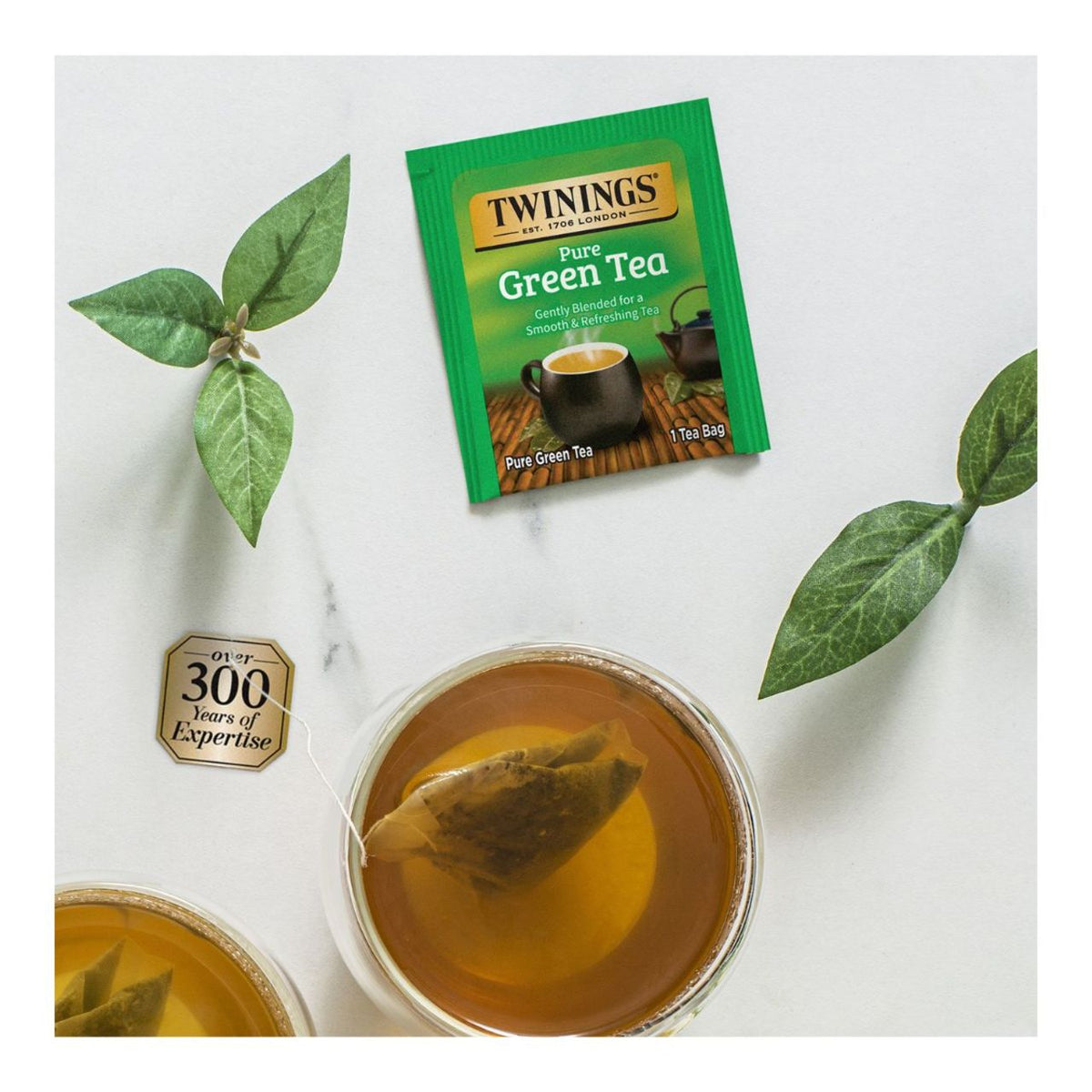 Twinings Pure Green Tea packet with a cup of tea and tea leaves on a white background