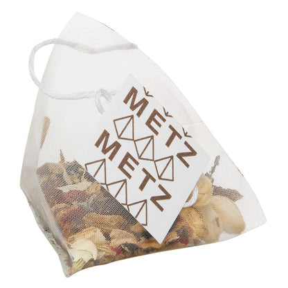 Tea bag filled with dried herbal tea and featuring a label for Metz.