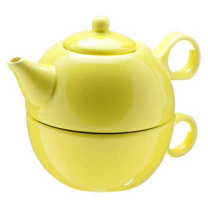 Ceramic yellow tea for one tea set featuring the teapot stacked on the matching cup on a white background