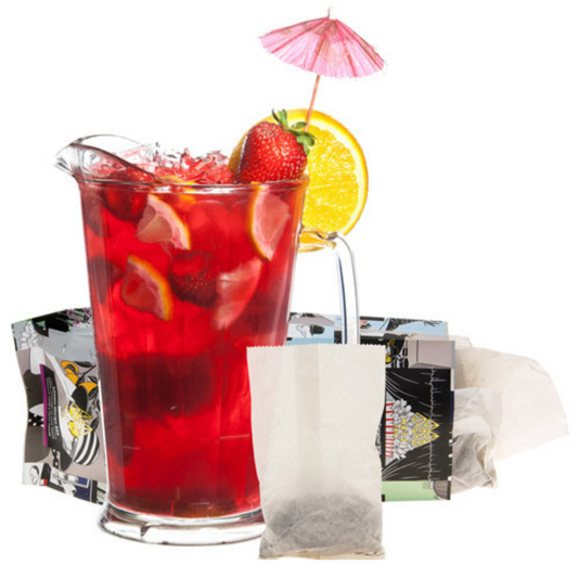 Red iced tea in a clear pitcher with fruit and a pink umbrella, tea bags, and a teabag packaging on a white background