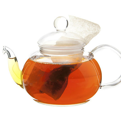 Clear glass teapot with a lid filled with tea on a white background
