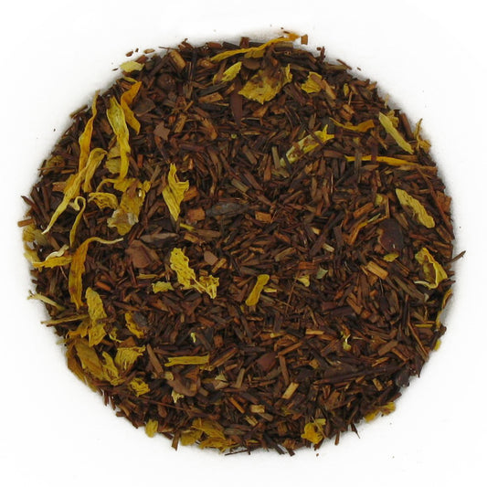 A close-up image of Godiva Roche flavored rooibos tea loose leaf, showing the blend of brown rooibos pieces, lighter rooibos strands, and added ingredients like petals and chocolate pieces.