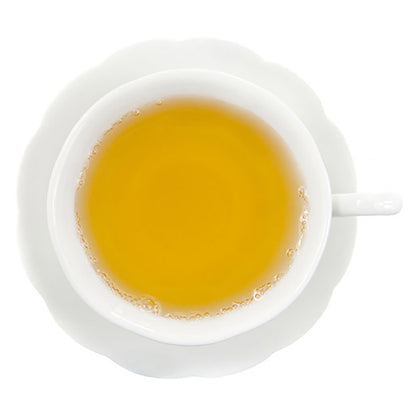 White teacup filled with yellow colored hot tea on a white background