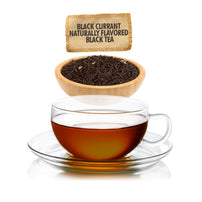 Glass cup of black currant flavored black tea with tea leaves and label.