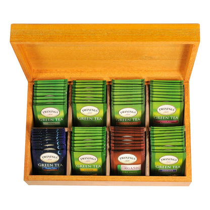 A wooden tea chest with multiple compartments, each filled with individually wrapped Twinings green tea bags.