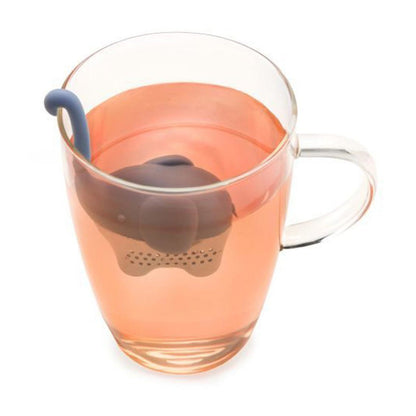 Blue elephant shaped tea infuser in a glass mug of pink colored tea.