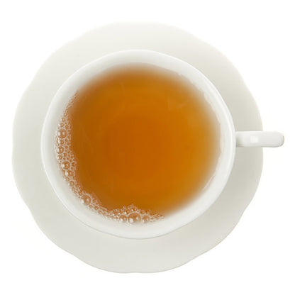 Top-down view of hot yellow colored tea in a white teacup on a white background