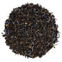 Black tea with blue flower petals on a white background