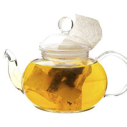 Yellow colored tea in a glass teapot with a teabag