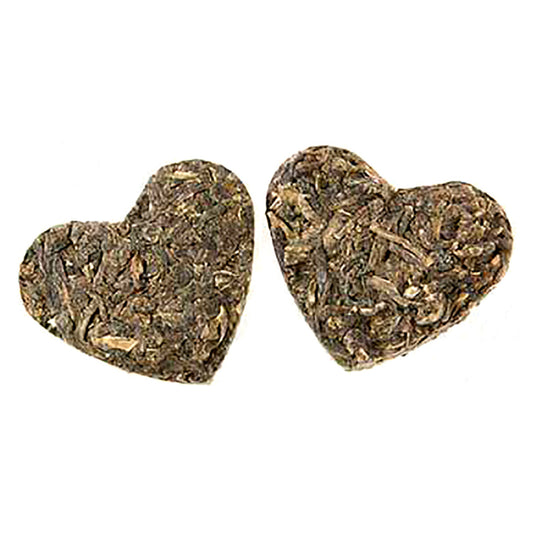 Green tea leaves pressed into two heart-shaped objects on a white background